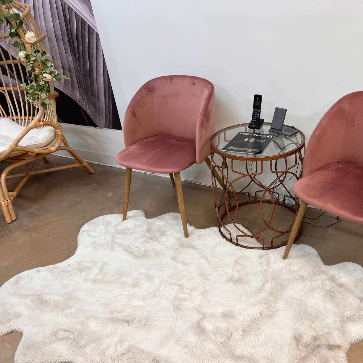 Two pink chairs positioned around a circular glass table on a white rug.