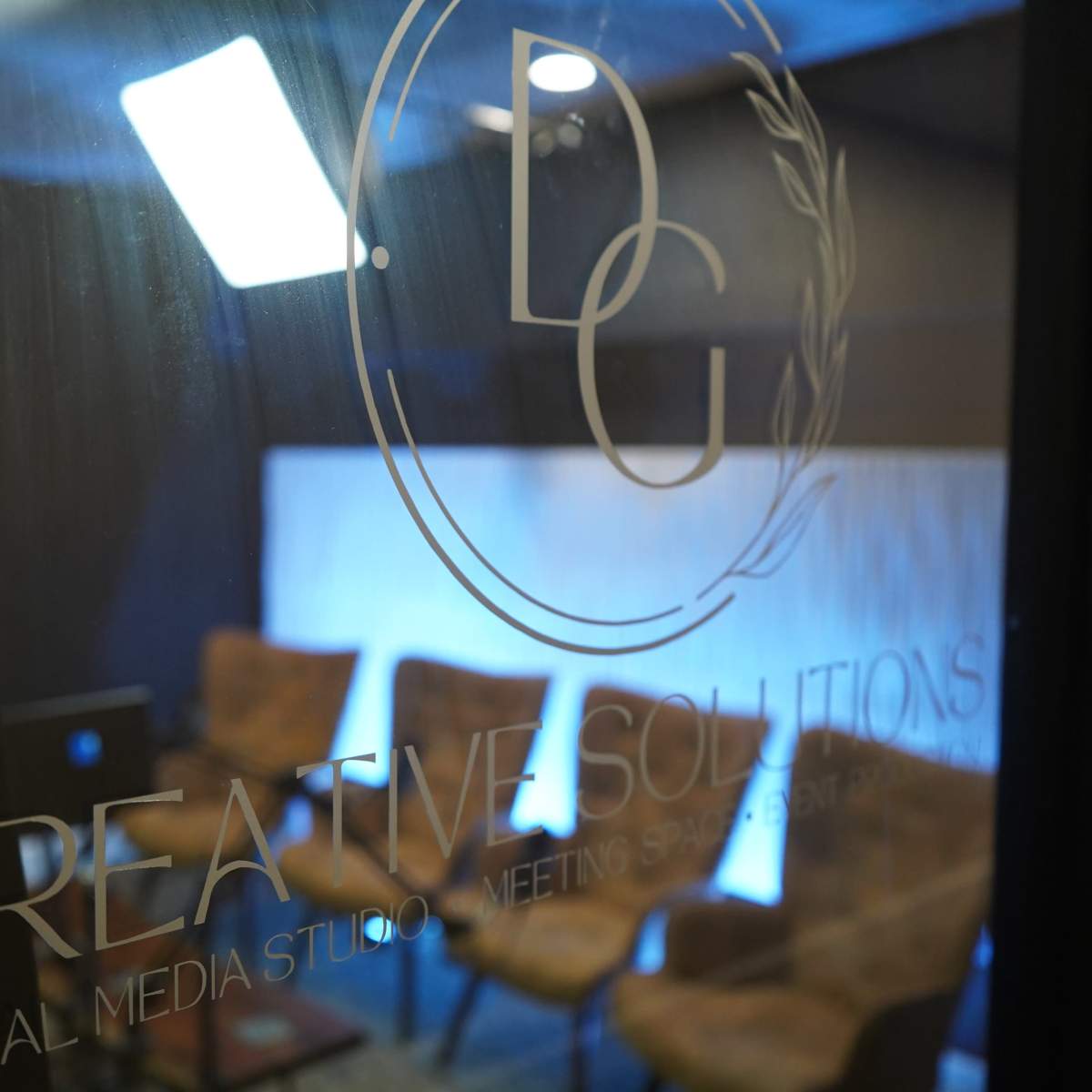 A studio space with a sign for "Creative Solutions" and several empty chairs arranged in front of a lit backdrop.