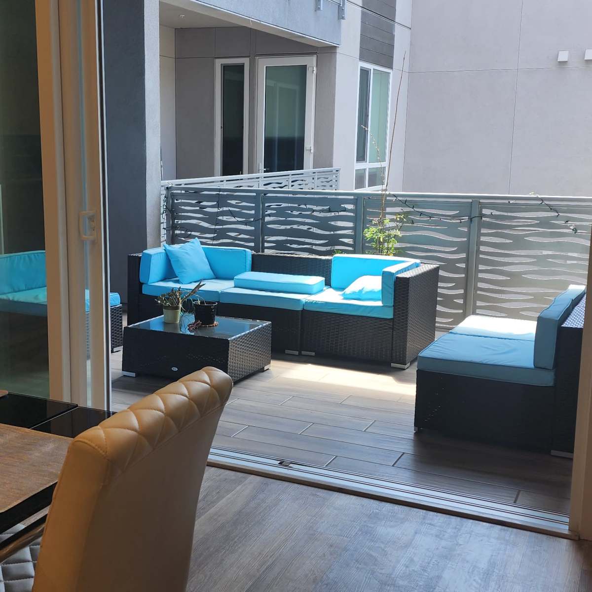 A dining area with a table and chairs that opens onto a balcony featuring modern outdoor furniture.