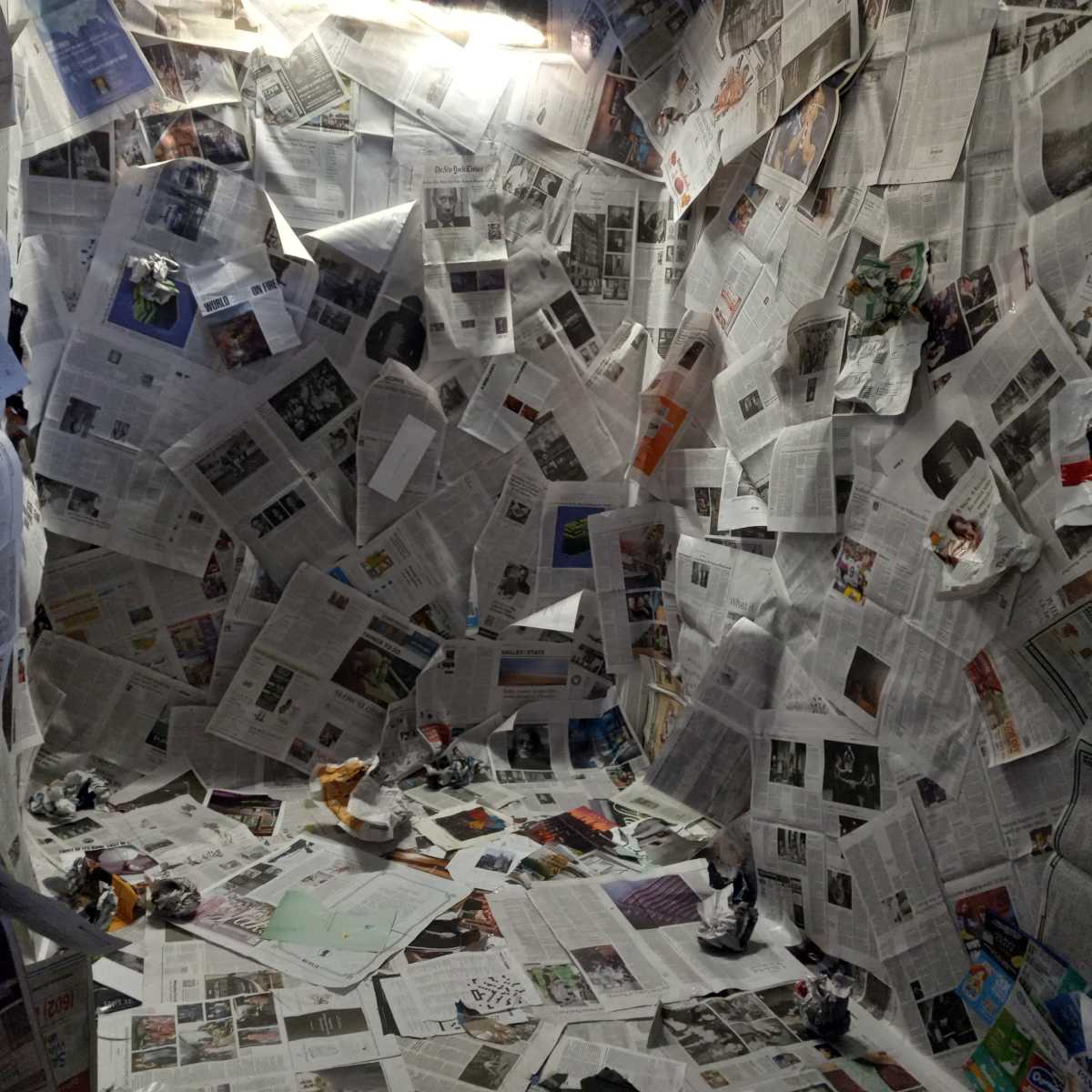 A small enclosed space covered with crumpled newspapers on the walls and floor.