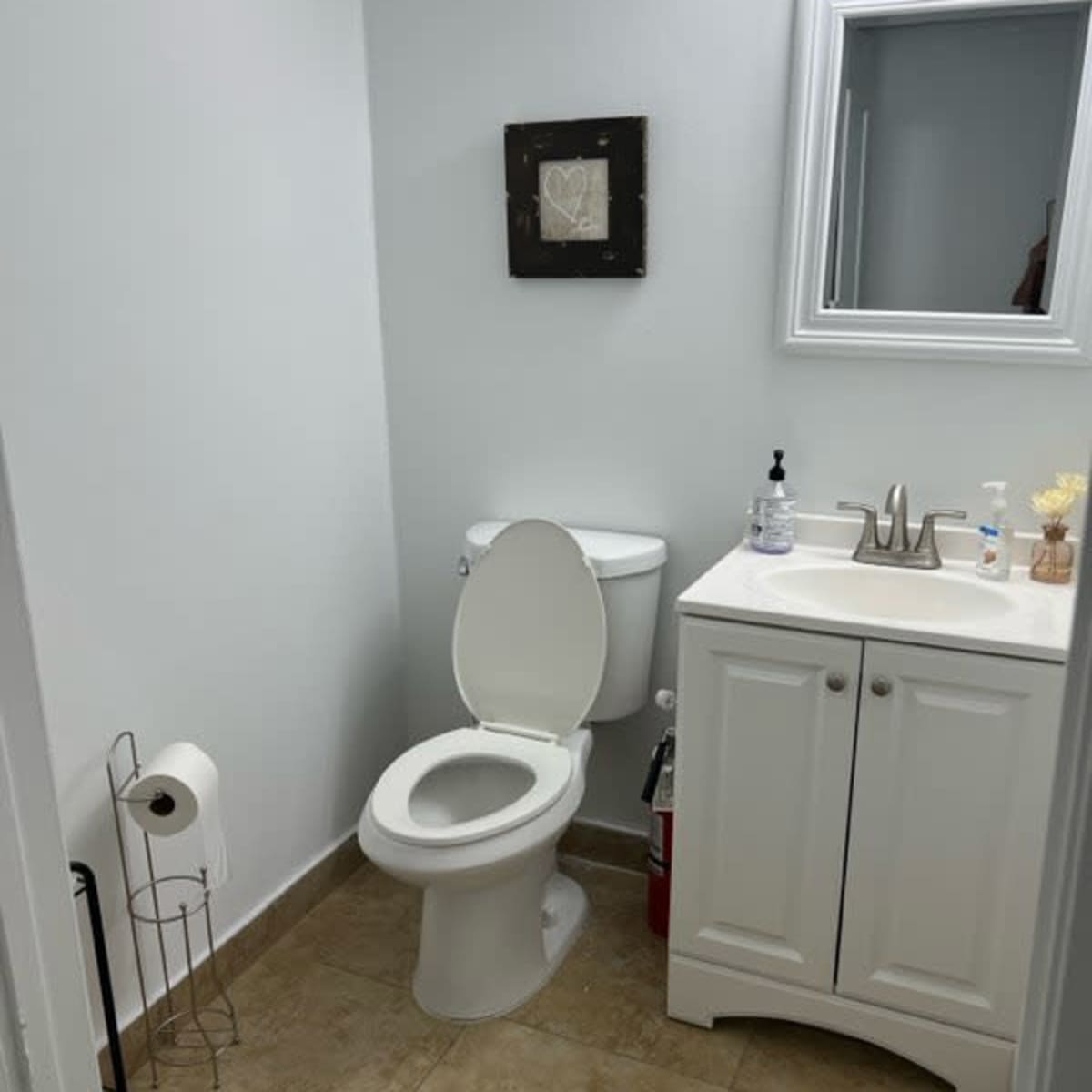 A small bathroom with a toilet, sink, and a framed picture on the wall.
