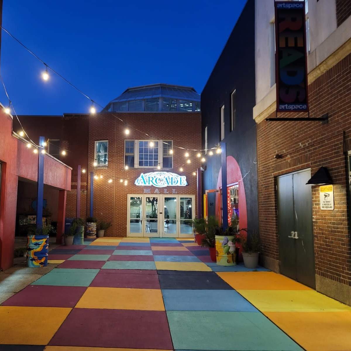 A vibrant courtyard with colorful tiles, string lights overhead, and an entrance labeled "ARCADE."