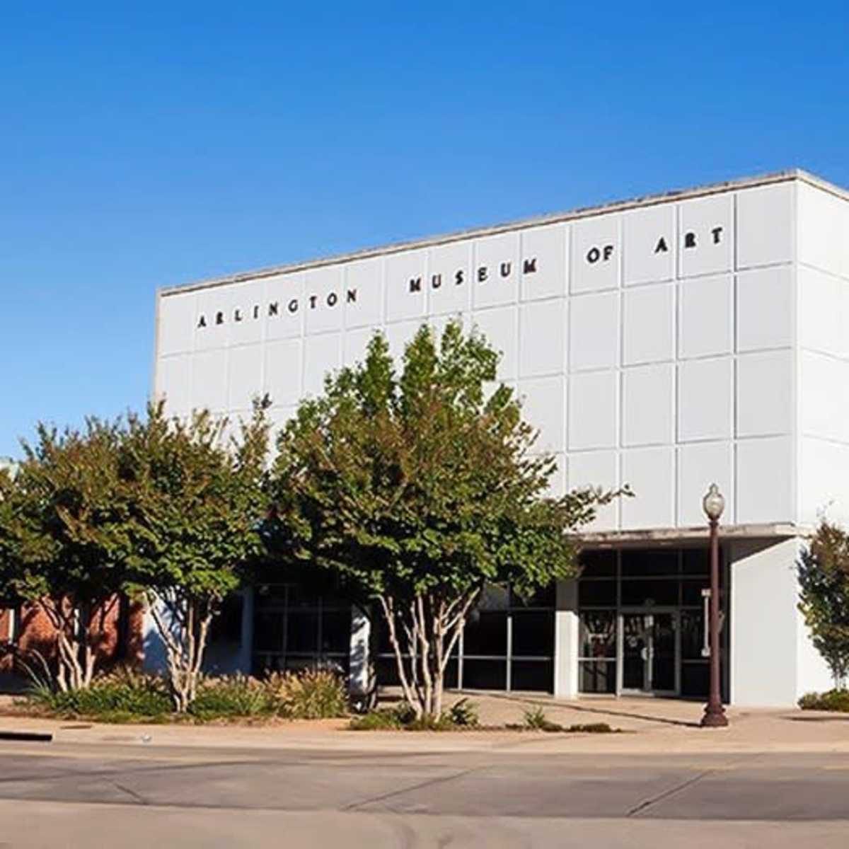 The Arlington Museum of Art features a modern white facade surrounded by well-maintained landscaping and clear blue skies.