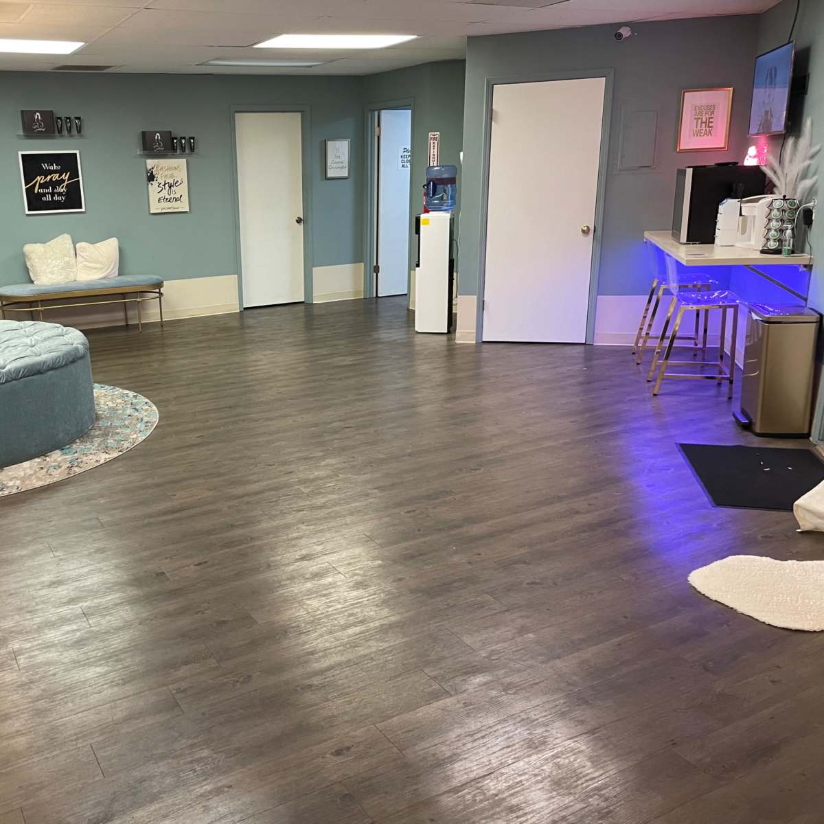 A spacious interior room with a circular, upholstered seating area, light wood flooring, and several doors leading to different areas.