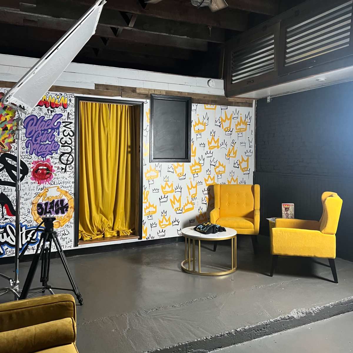A stylish interior with vibrant yellow chairs, a small round table, and a backdrop featuring graffiti-style patterns on the walls.