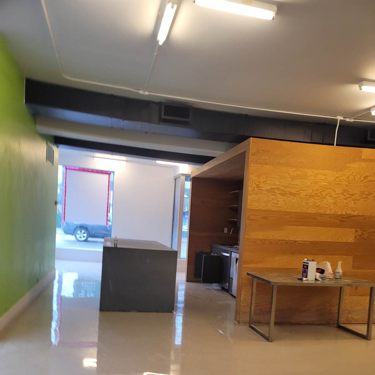A spacious interior with a green wall, a wooden partition, and a table in an unfinished space.