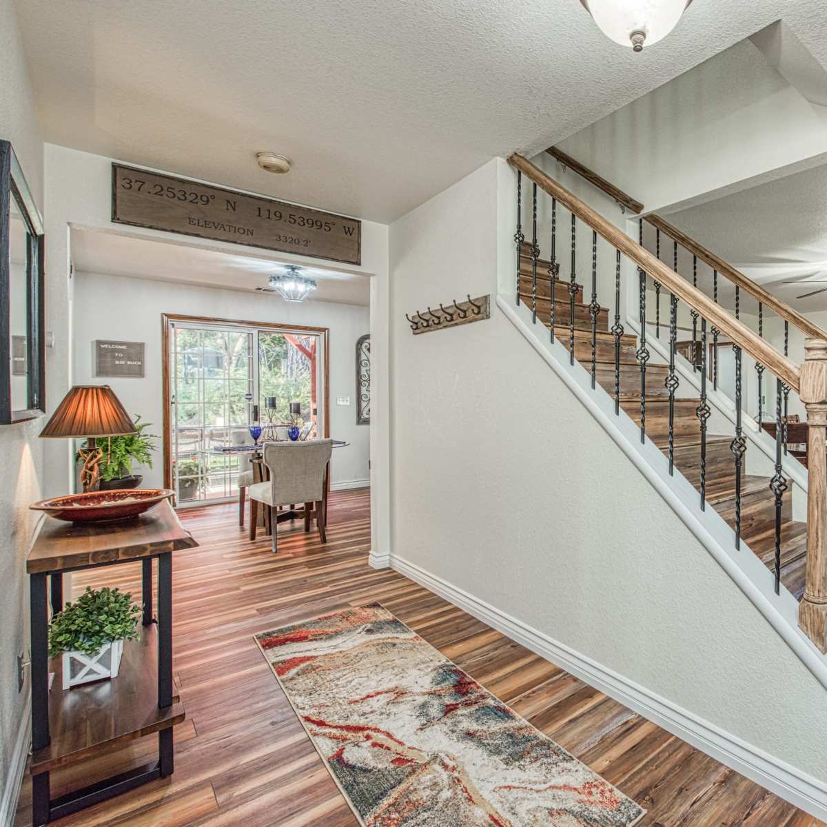 A well-lit entryway with a staircase leading to an upper level, and a dining area visible in the background.
