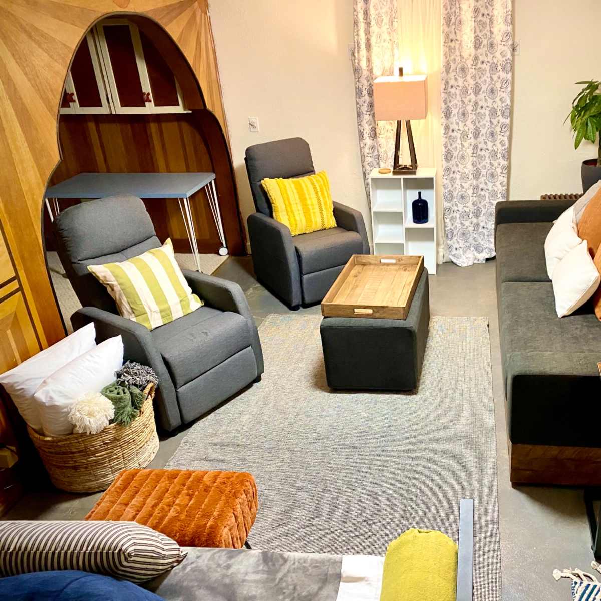 A cozy living room setup with multiple seating options, a coffee table, and decorative elements, illuminated by soft lighting.