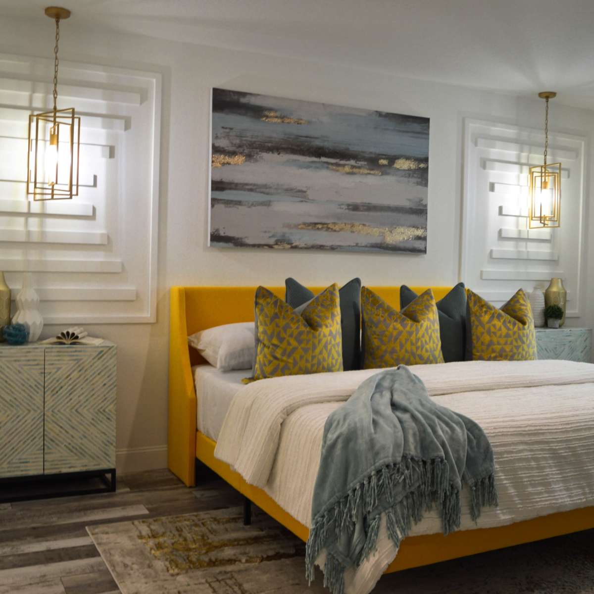 A bright bedroom featuring a yellow bed with decorative pillows, flanked by nightstands and illuminated by pendant lights.