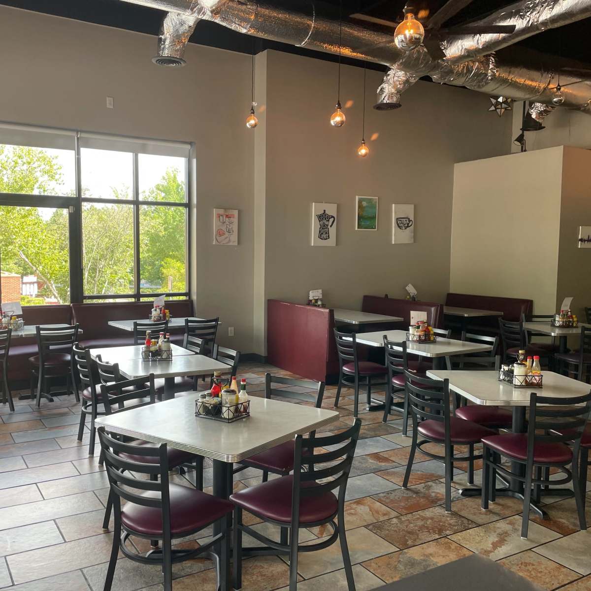 A dining area in a restaurant with several tables and chairs arranged near large windows.