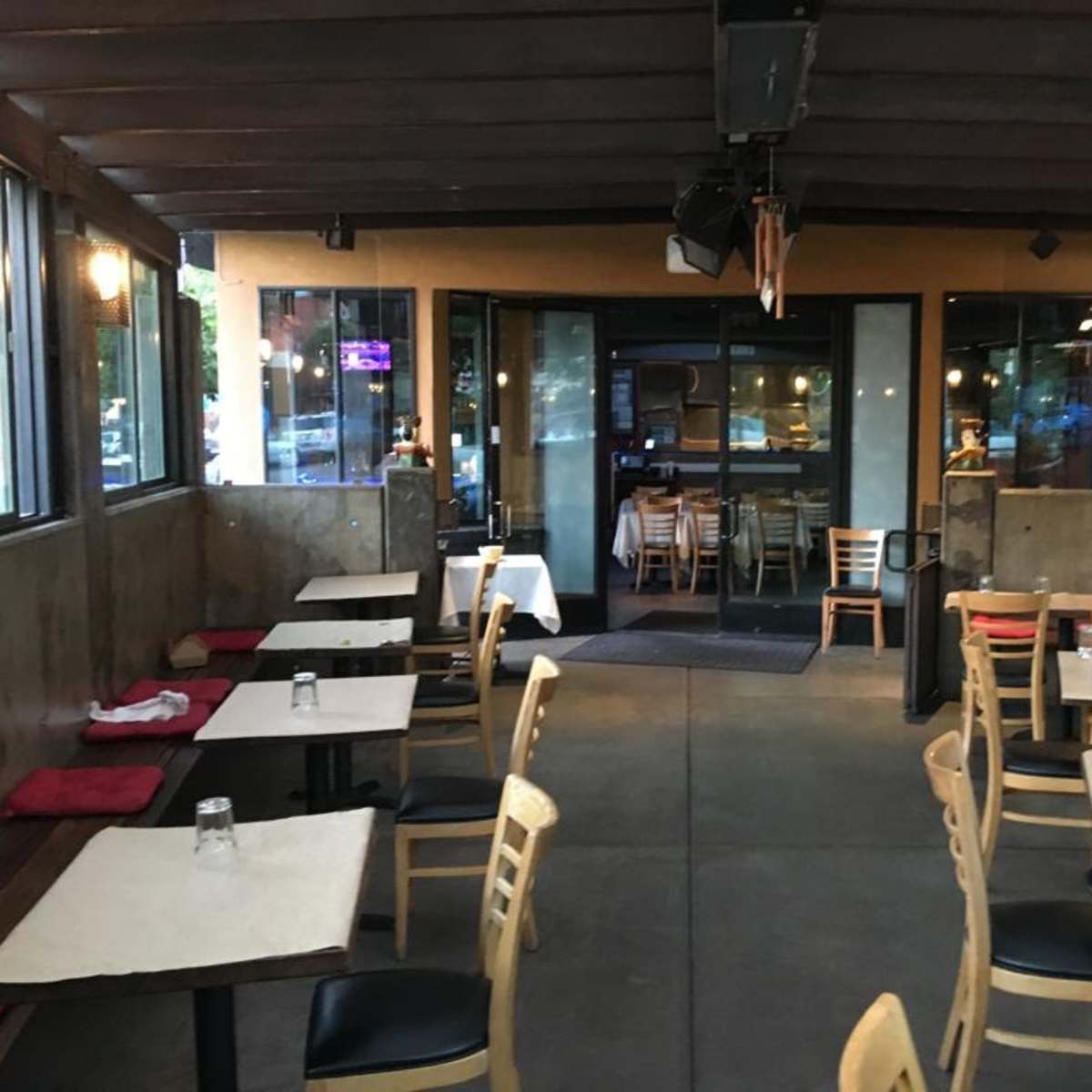 An empty restaurant interior with wooden tables and chairs arranged neatly in a dimly lit space.