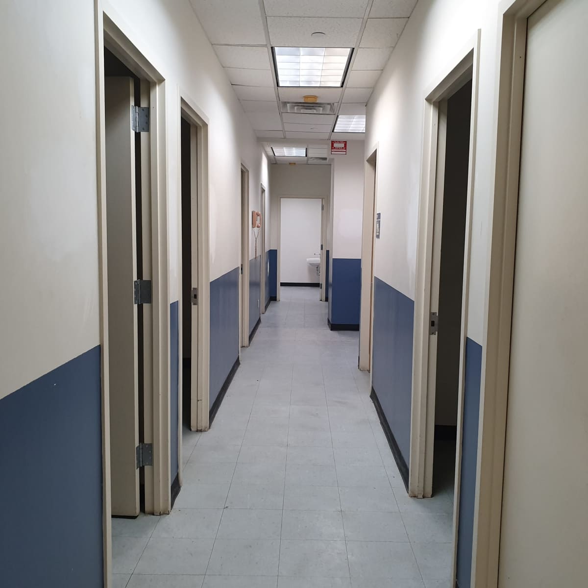 A long corridor with several doors on either side and a door at the end.