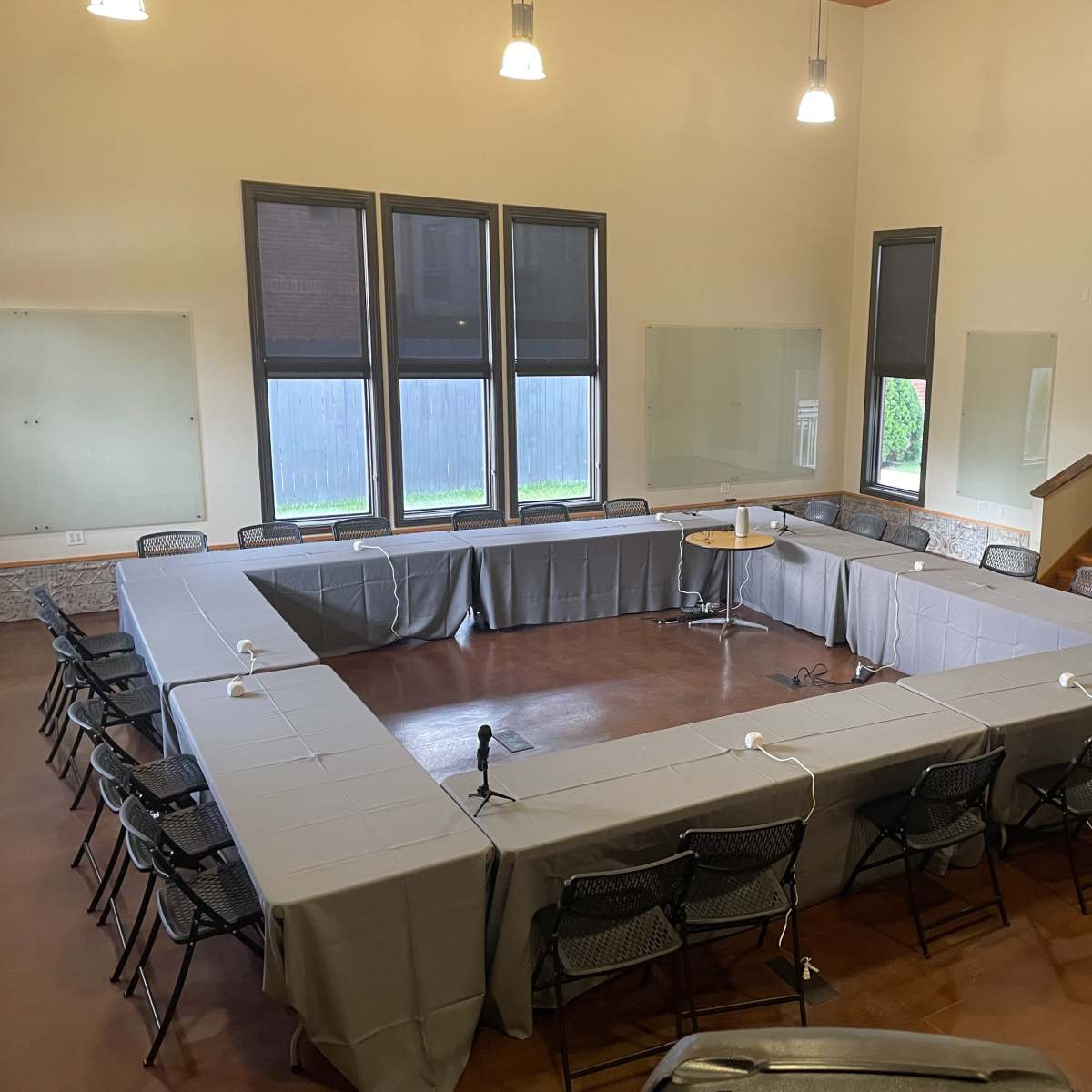 A large meeting room set up with an arrangement of tables and chairs in an open rectangular layout.
