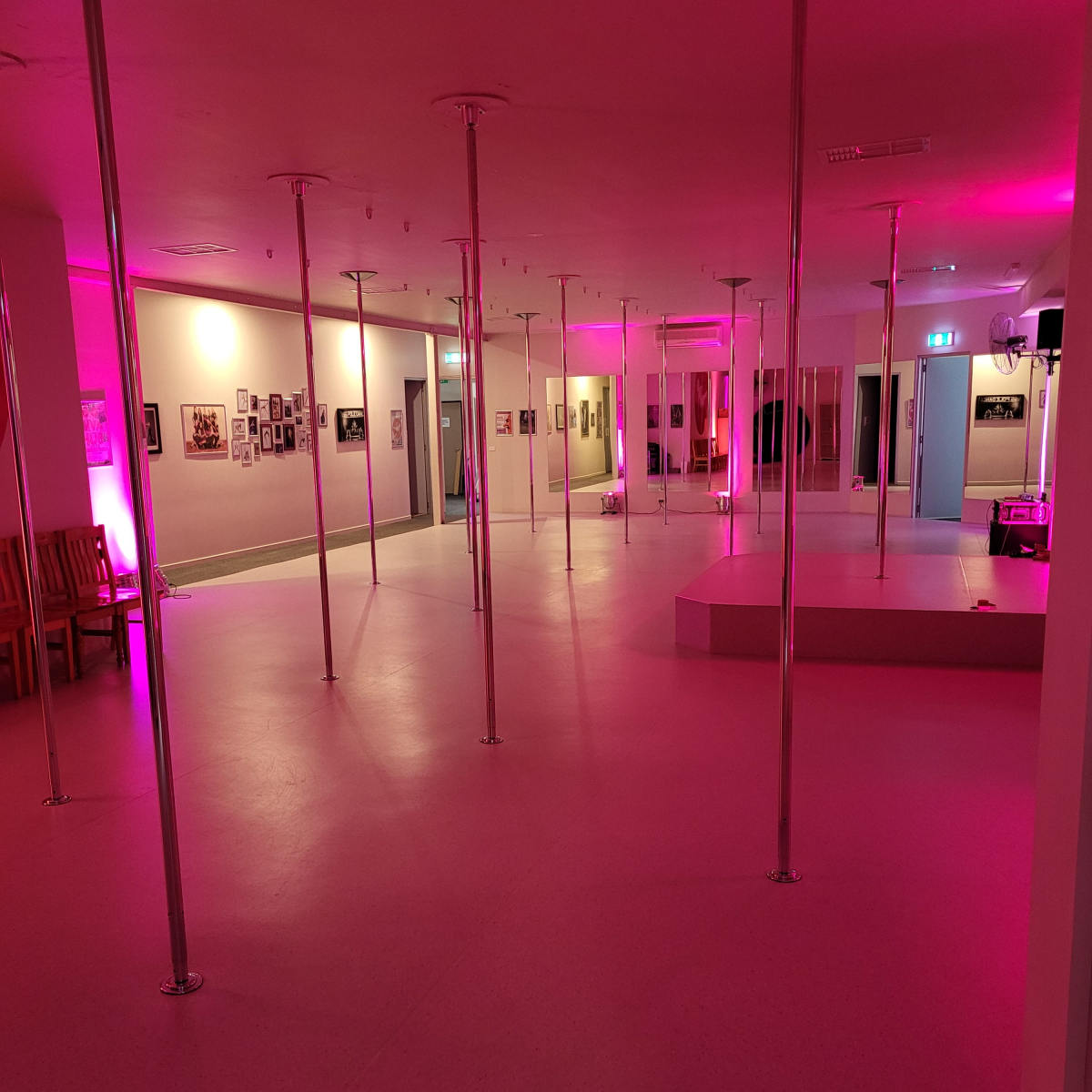 An empty studio space featuring multiple vertical poles and purple lighting.