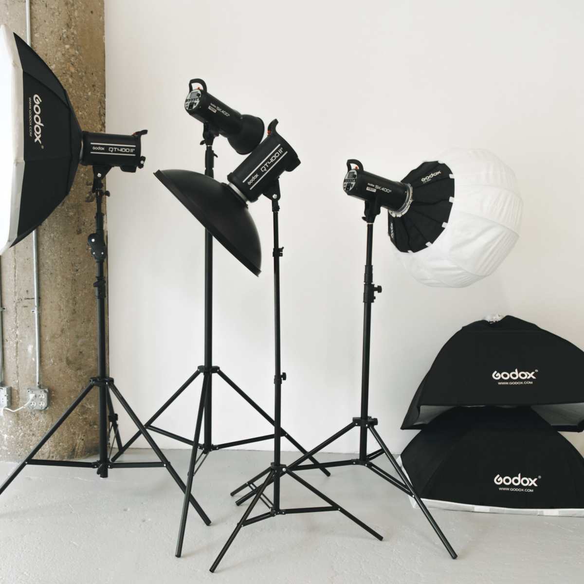 Several photography lights and softboxes arranged next to a plain white wall.