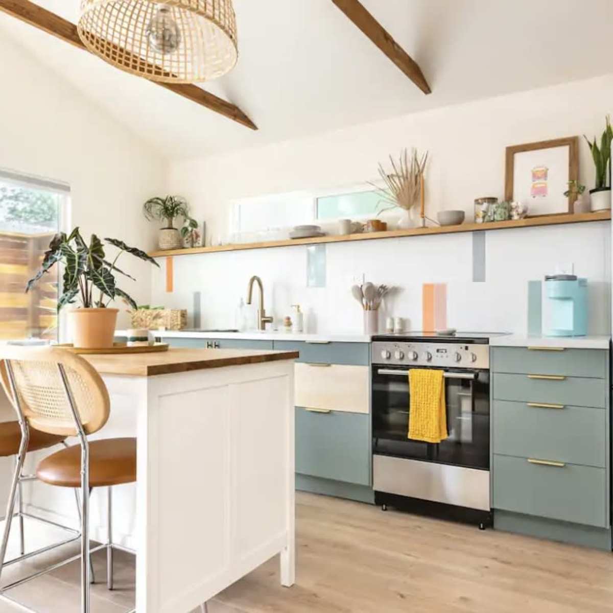 A modern kitchen features a central island with bar stools, a stove, and open shelving adorned with plants and decorative items.