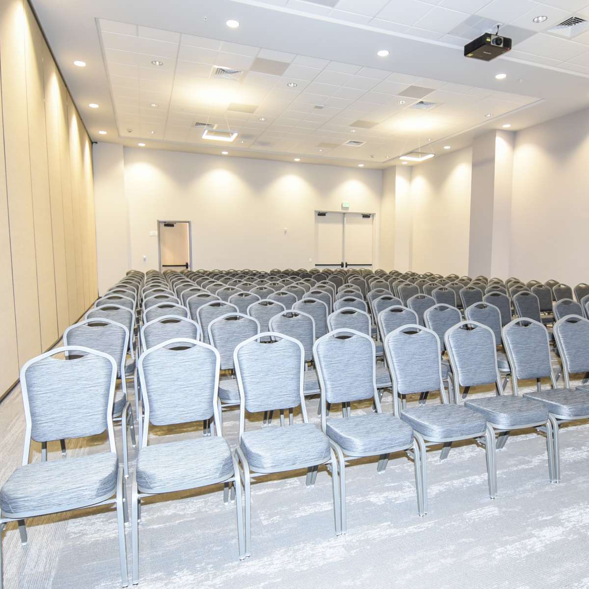 A row of gray chairs is neatly arranged in a conference room.