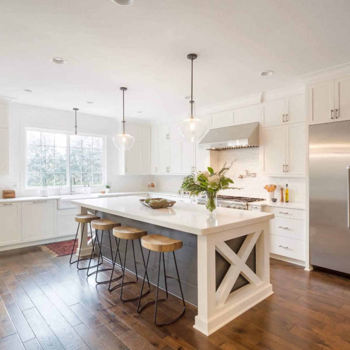 A modern kitchen featuring white cabinetry, a large central island with bar stools, and stainless steel appliances.