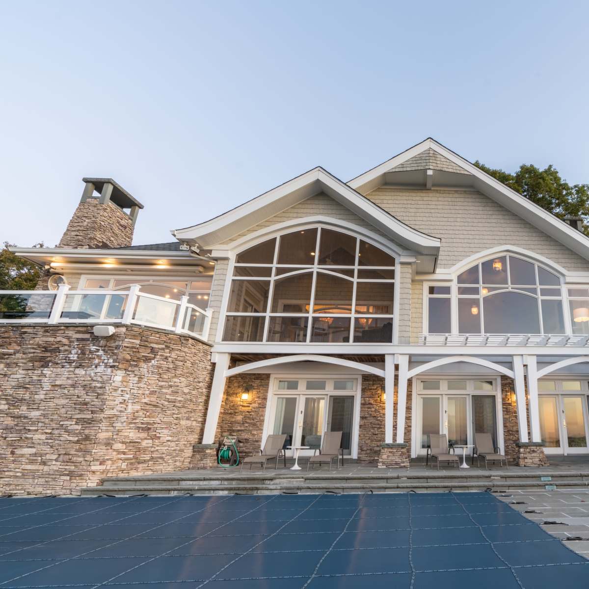 A large, modern house with a stone facade and multiple large windows, set against a clear sky.