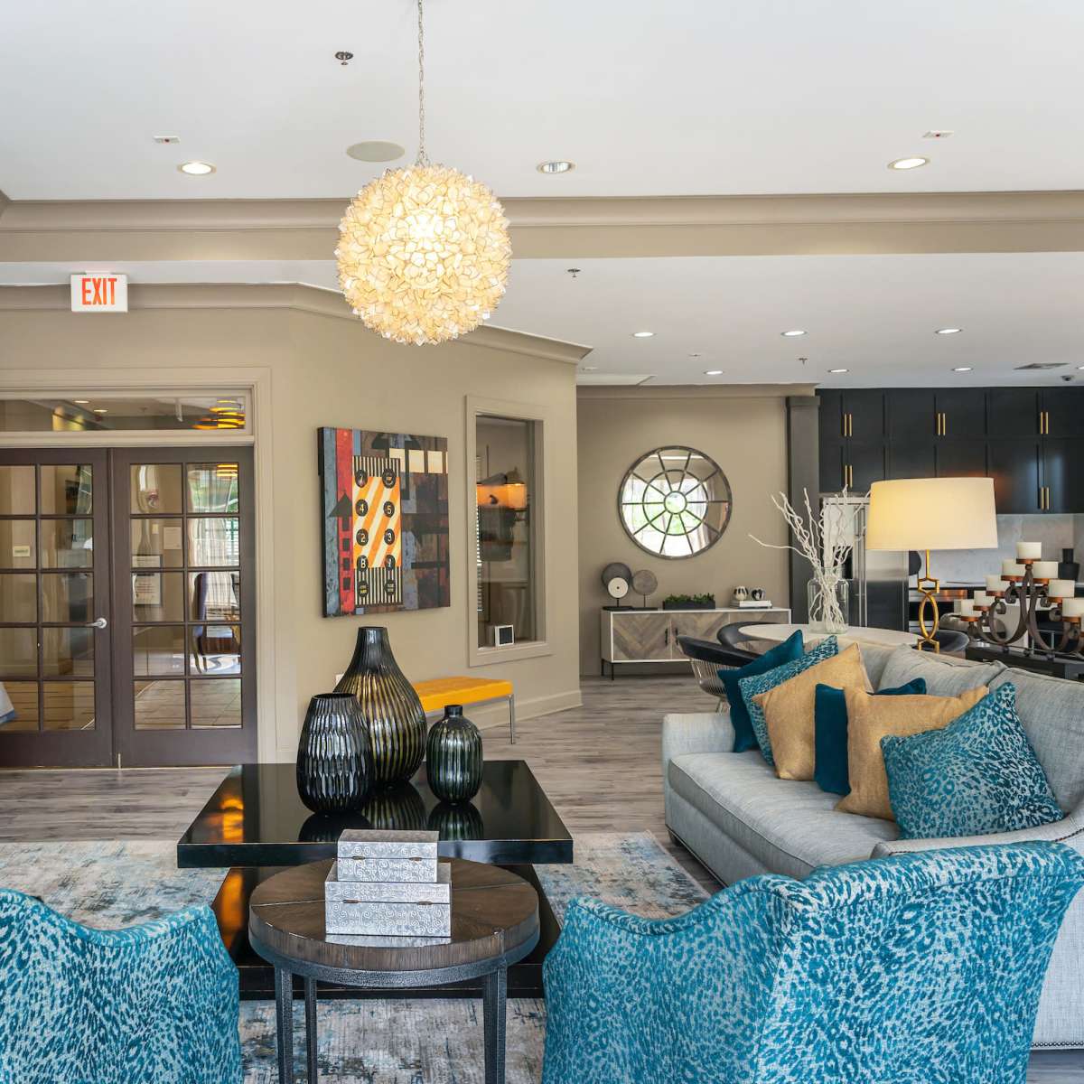 A modern lounge area featuring a seating arrangement with blue and gold accents, decorative vases, and a circular window.