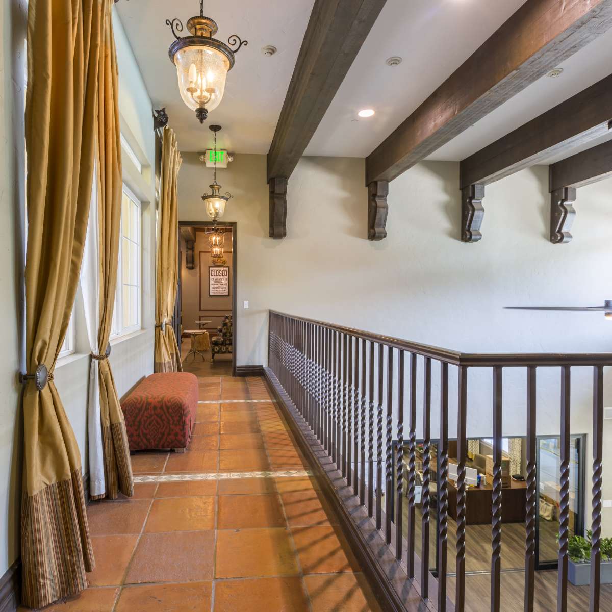 A hallway with wooden beams, a tiled floor, and decorative lighting, leading to an open area with visible furniture.