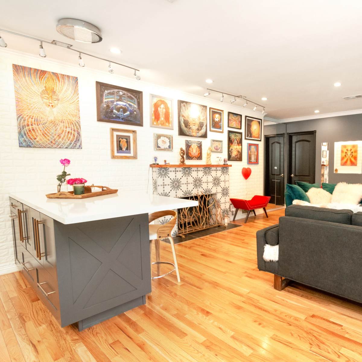 A modern living room features a minimalist sofa, a decorative fireplace, and an arrangement of colorful artwork on the walls.