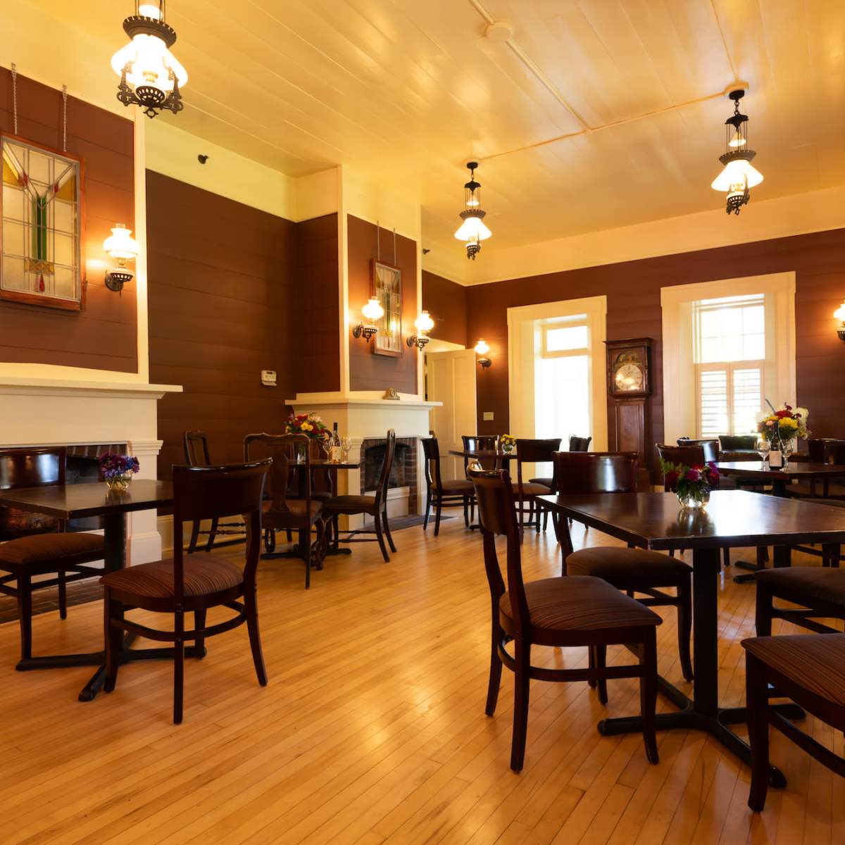 A spacious, warmly lit dining area with wooden tables and chairs arranged around a polished wooden floor.