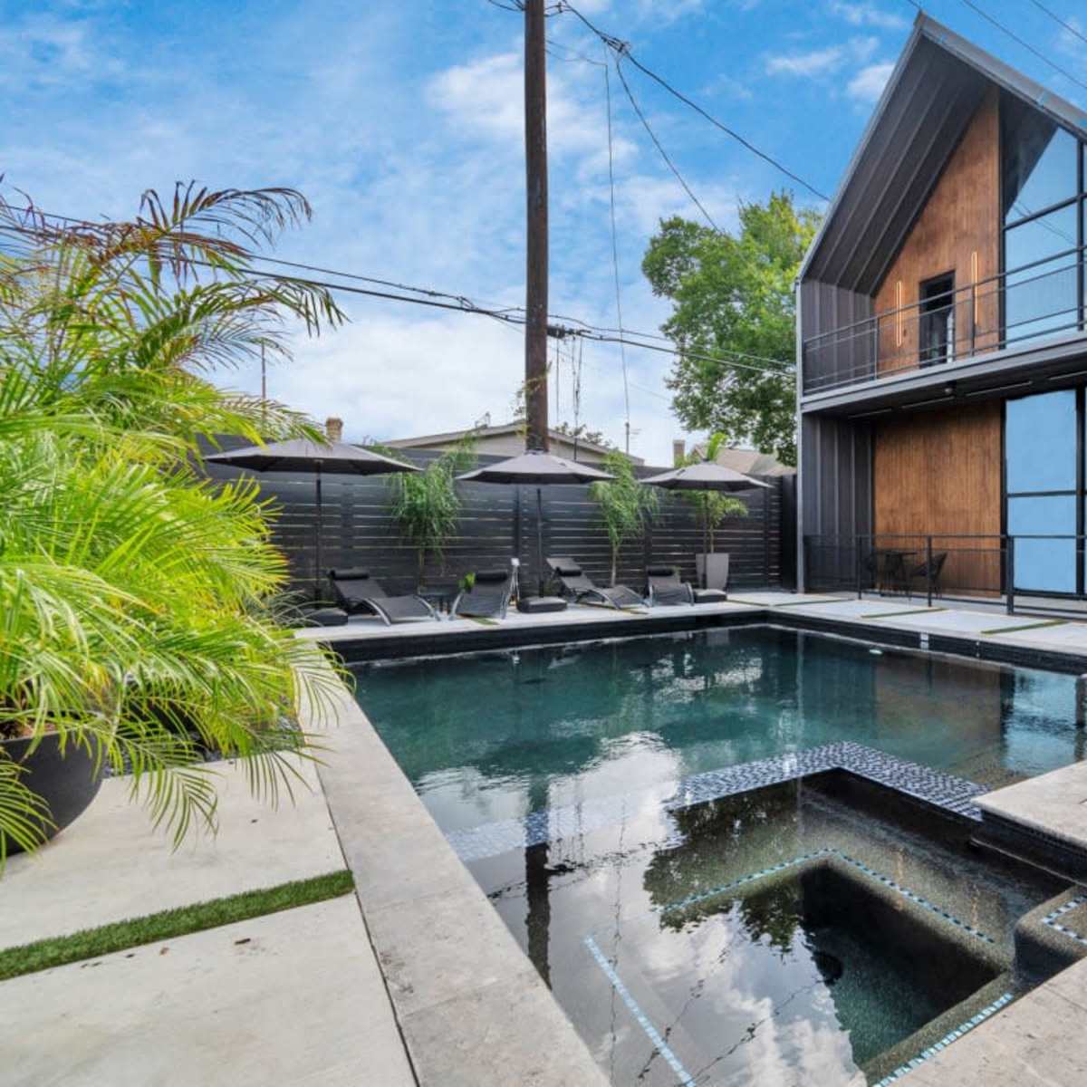 A modern house with a pool and spa surrounded by sleek landscaping.