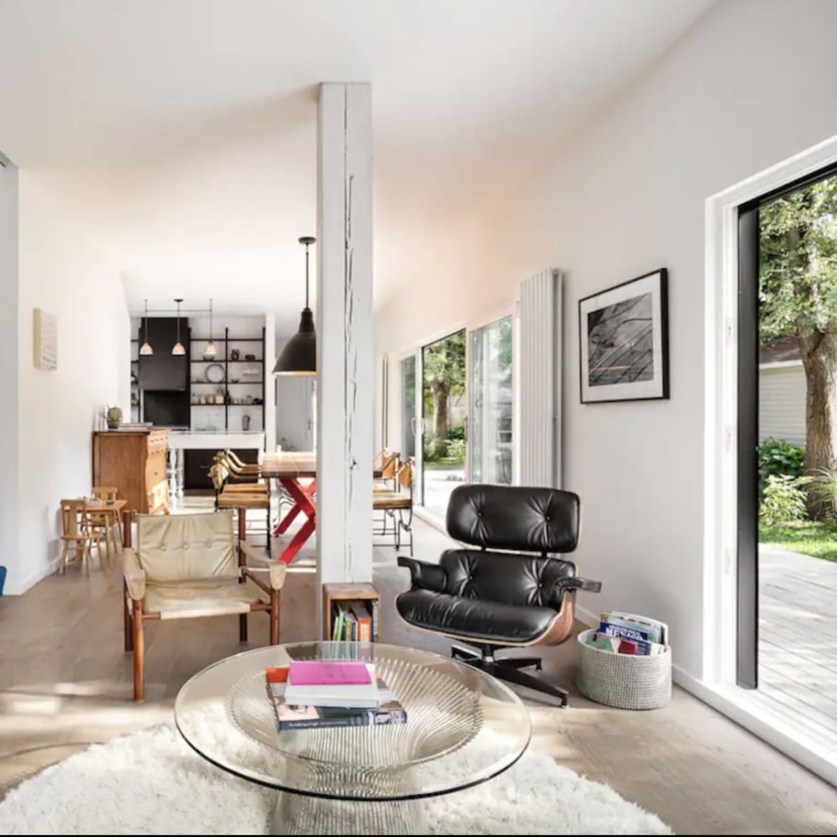 A modern living space with a seating area, dining area, and large windows overlooking a backyard.