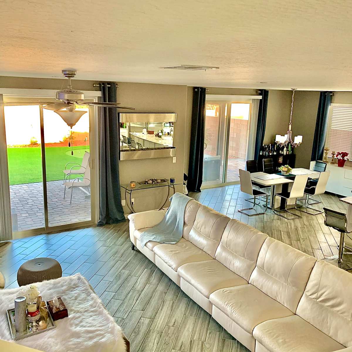 A modern living space with a white sofa, a dining area, and large glass doors leading to a backyard.