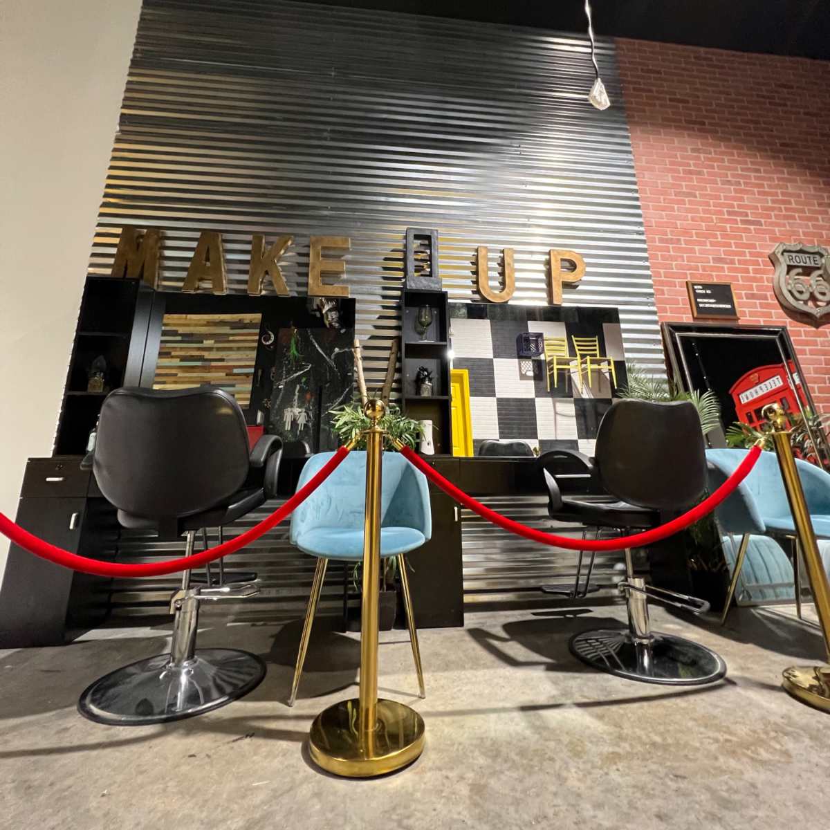 A modern makeup display area with chairs, a counter, and decorative elements, surrounded by a red rope barrier.