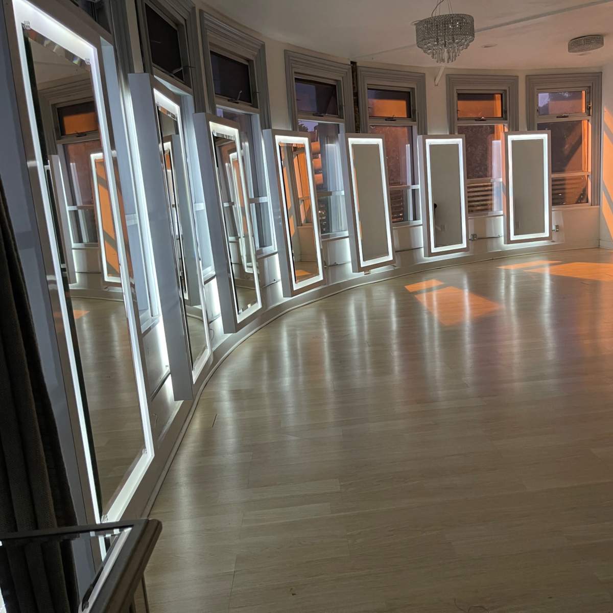 A curved room with several large mirrors positioned along the walls, reflecting light from the windows.