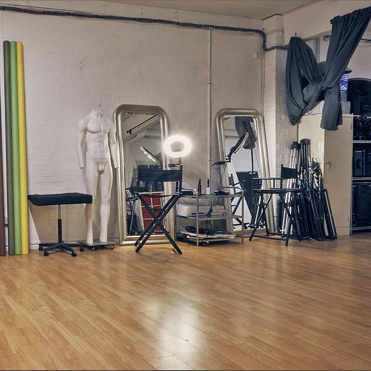 A studio space featuring a light-colored sofa, a colorful backdrop, and various photography equipment.