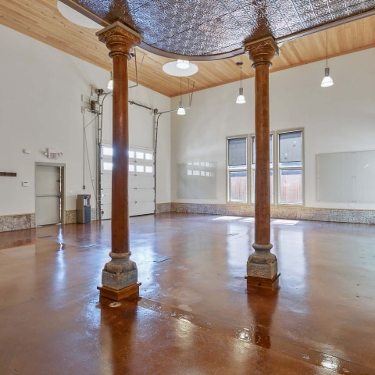 An empty, spacious room with polished concrete floors, two decorative columns, and large windows.