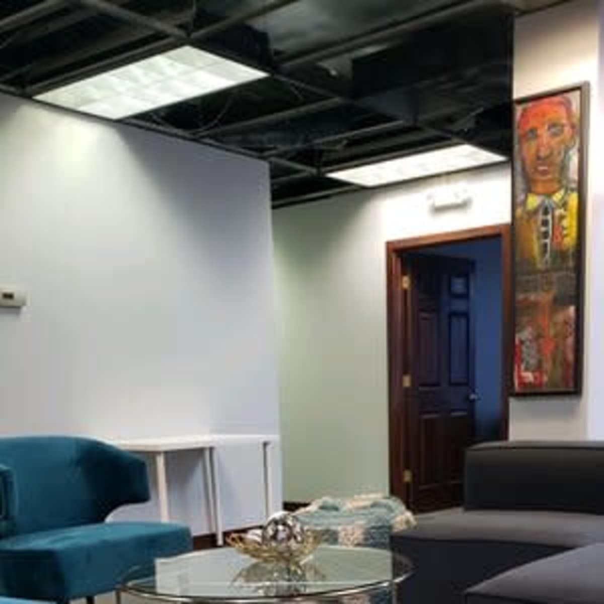 A modern office interior featuring two sofas, a glass coffee table, and a decorative rug.