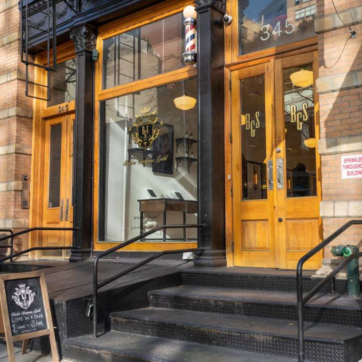 The entrance of a barbershop with large glass doors and a sign displaying the business name, located at 345.