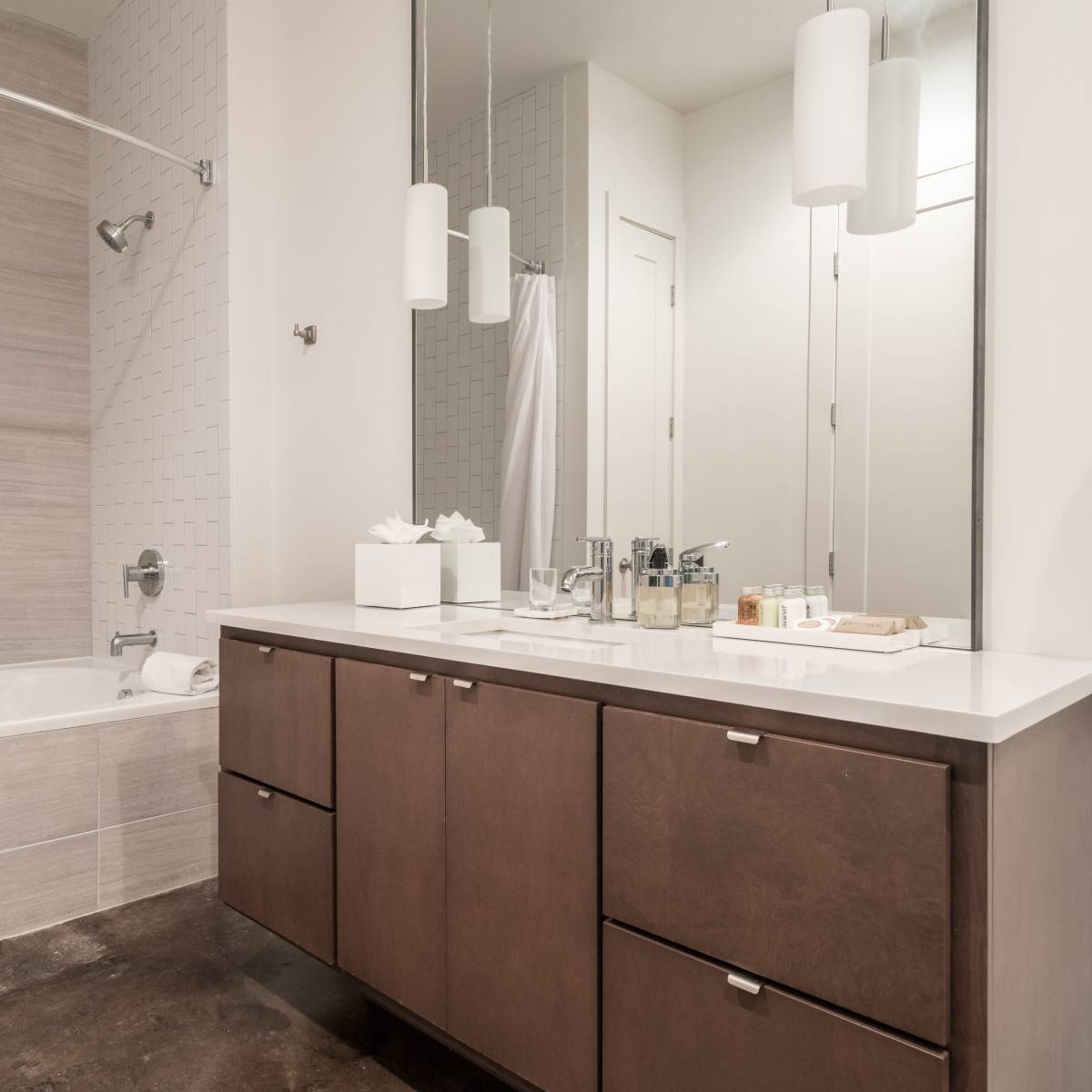 A modern bathroom with a bathtub, a shower curtain, a double sink vanity with dark wood cabinetry, and a large mirror.