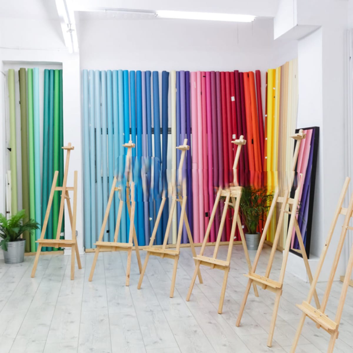 A bright art studio featuring wooden easels arranged in rows against a backdrop of colorful vertical panels.