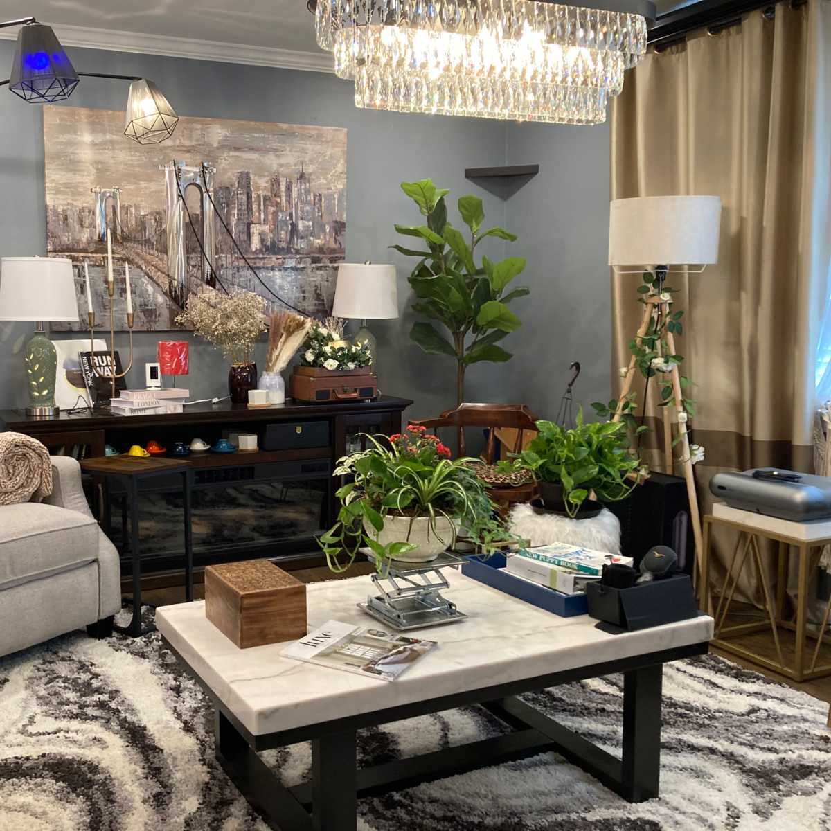 A modern living room with a gray armchair, a coffee table with a marble top, various indoor plants, and decorative wall art featuring a city skyline.