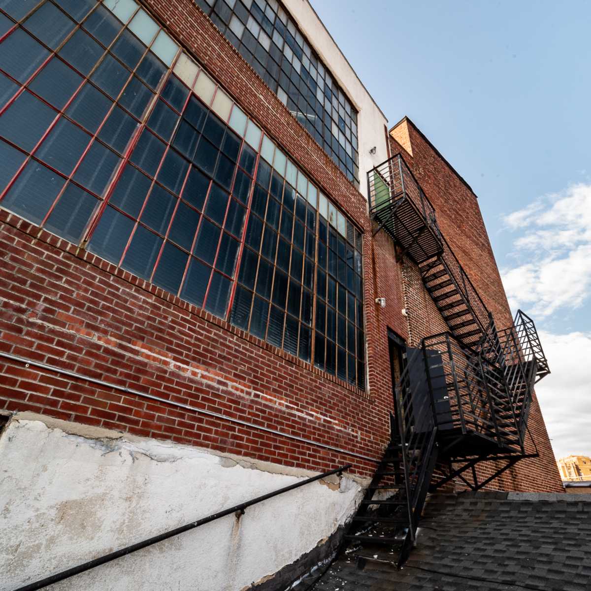 A brick building with large windows and an external metal fire escape.