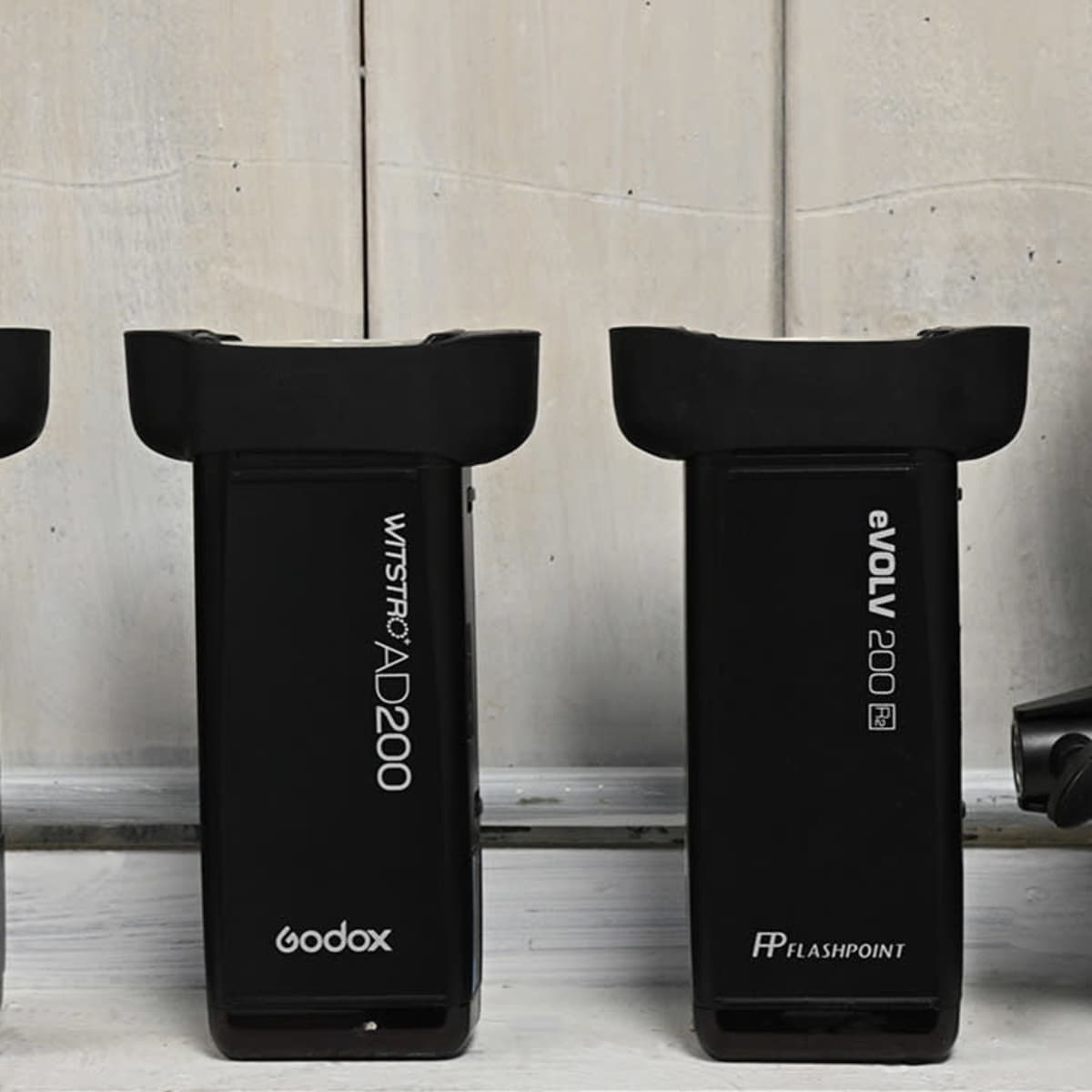 Four photography light units lined up against a wooden background.
