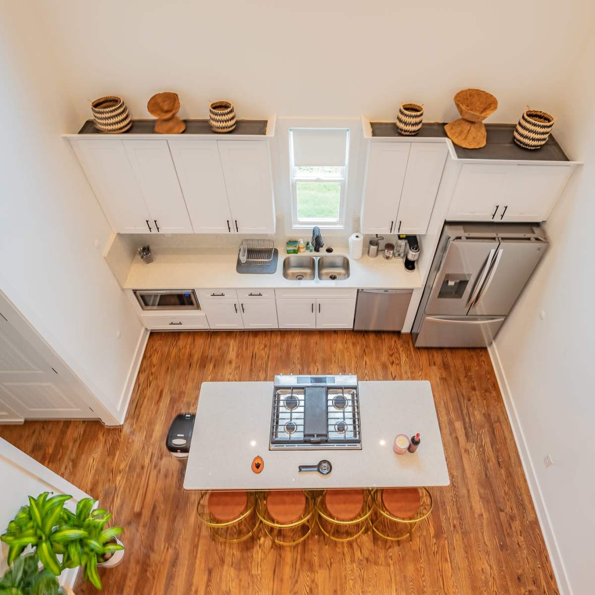 A modern kitchen with a central island, stainless steel appliances, and wooden flooring.