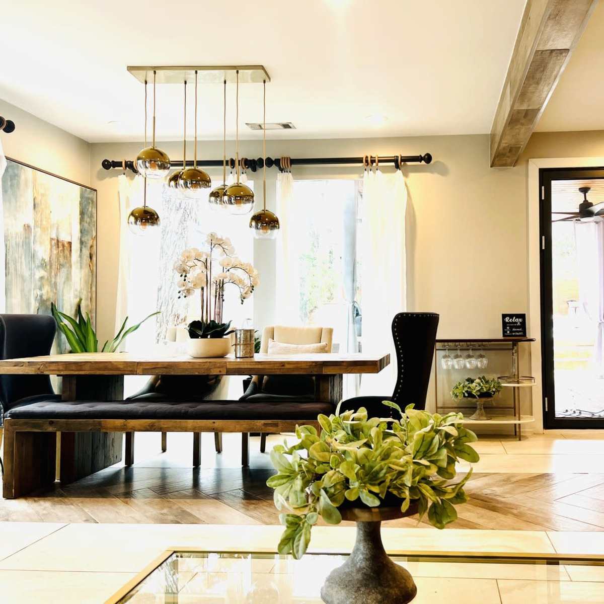 A modern dining area featuring a wooden table with decorative chairs, pendant lighting, and large glass doors leading to an outdoor space.