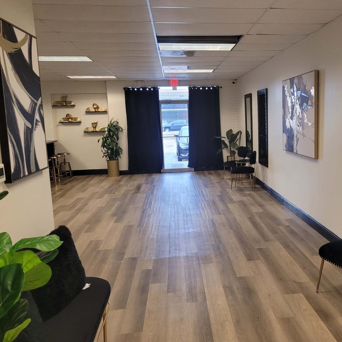A spacious, well-lit hallway with wooden flooring, featuring black curtains at the entrance and modern decor on the walls.