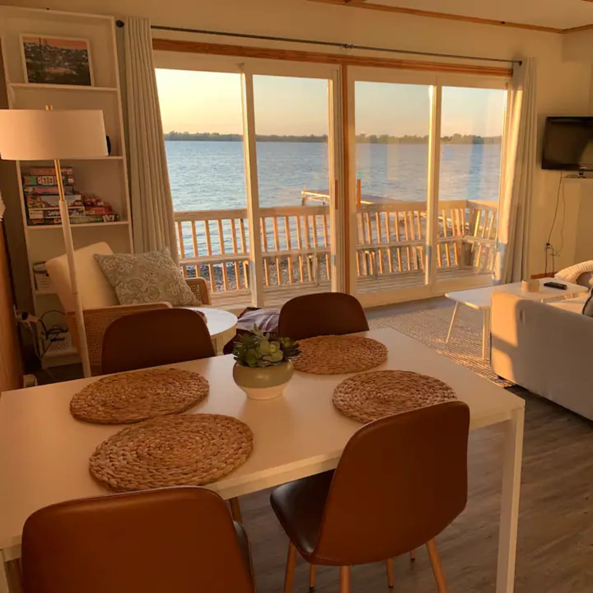 A cozy living space with a dining area, a couch, and large sliding glass doors overlooking a waterfront view.