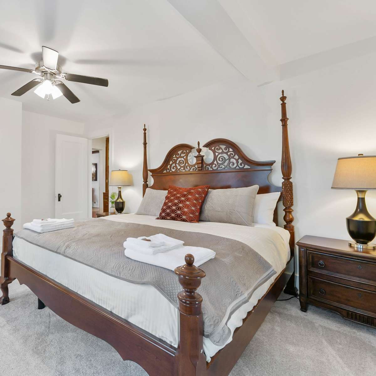 A well-furnished bedroom with a large wooden bed, bedside lamps, a television mounted on the wall, and a radiator.