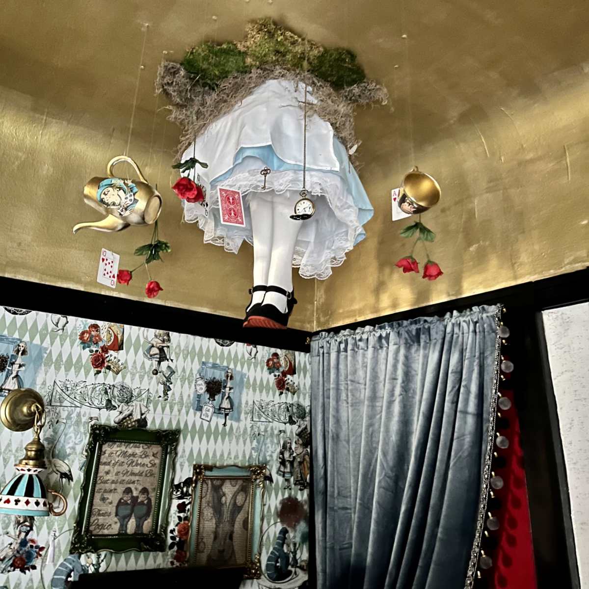 The ceiling features a mannequin dressed in a white dress and red shoes, surrounded by hanging decorations and floral elements.