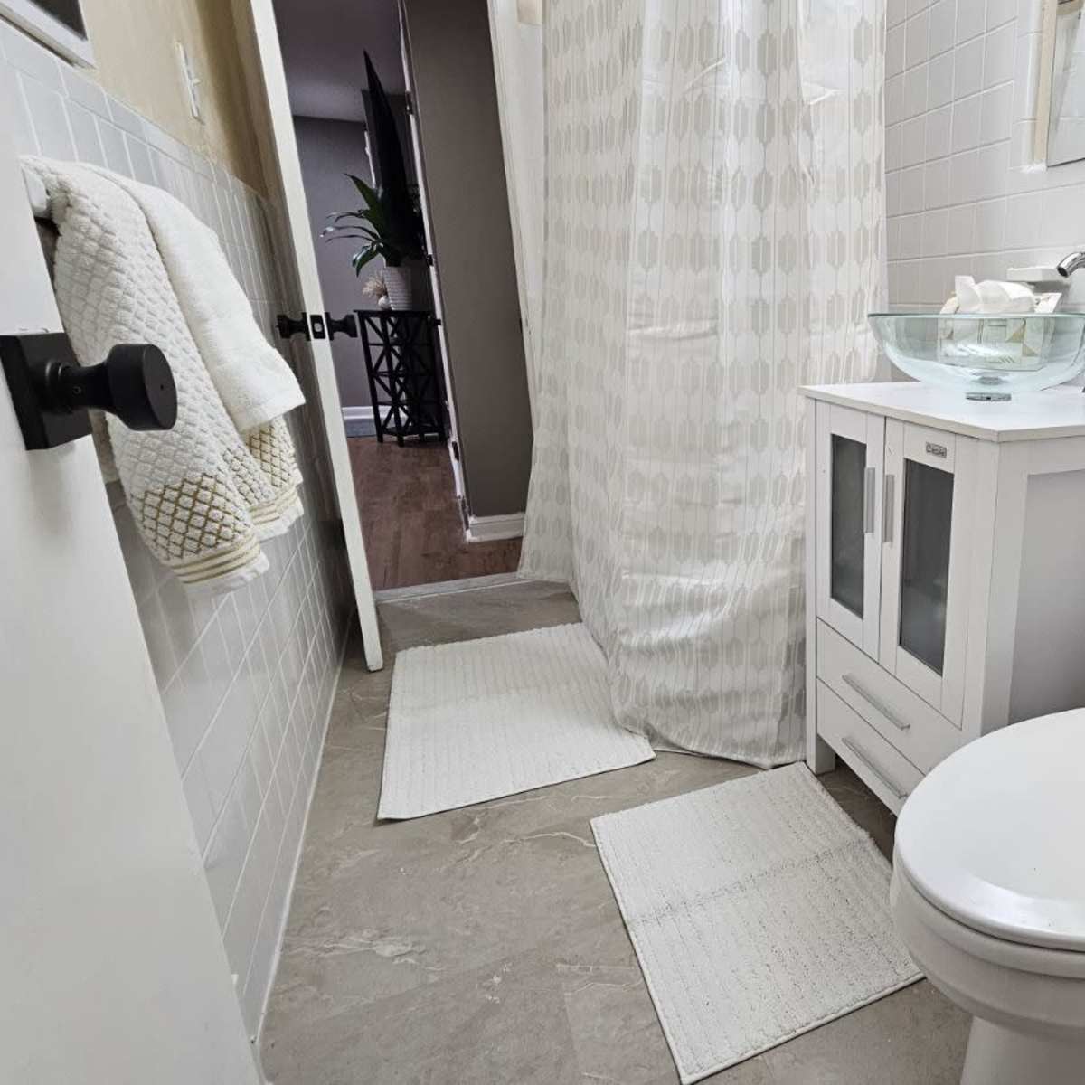 A small bathroom featuring a toilet, a white sink with a bowl design, and a shower area separated by a curtain.