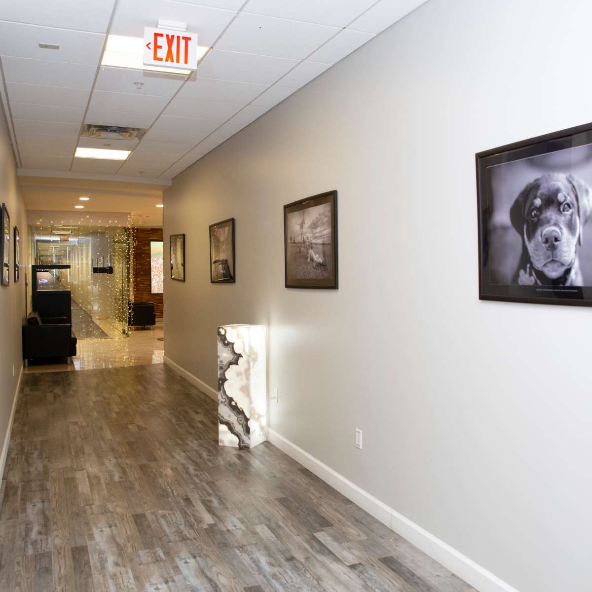 A well-lit hallway features framed black-and-white photographs on the walls and a unique illuminated display at one end.
