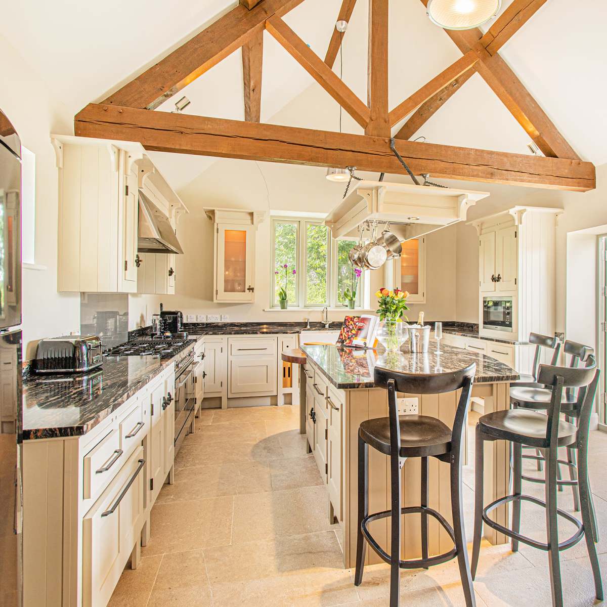 The kitchen features a spacious layout with a large island, wooden beams, and sliding glass doors that open to a patio.